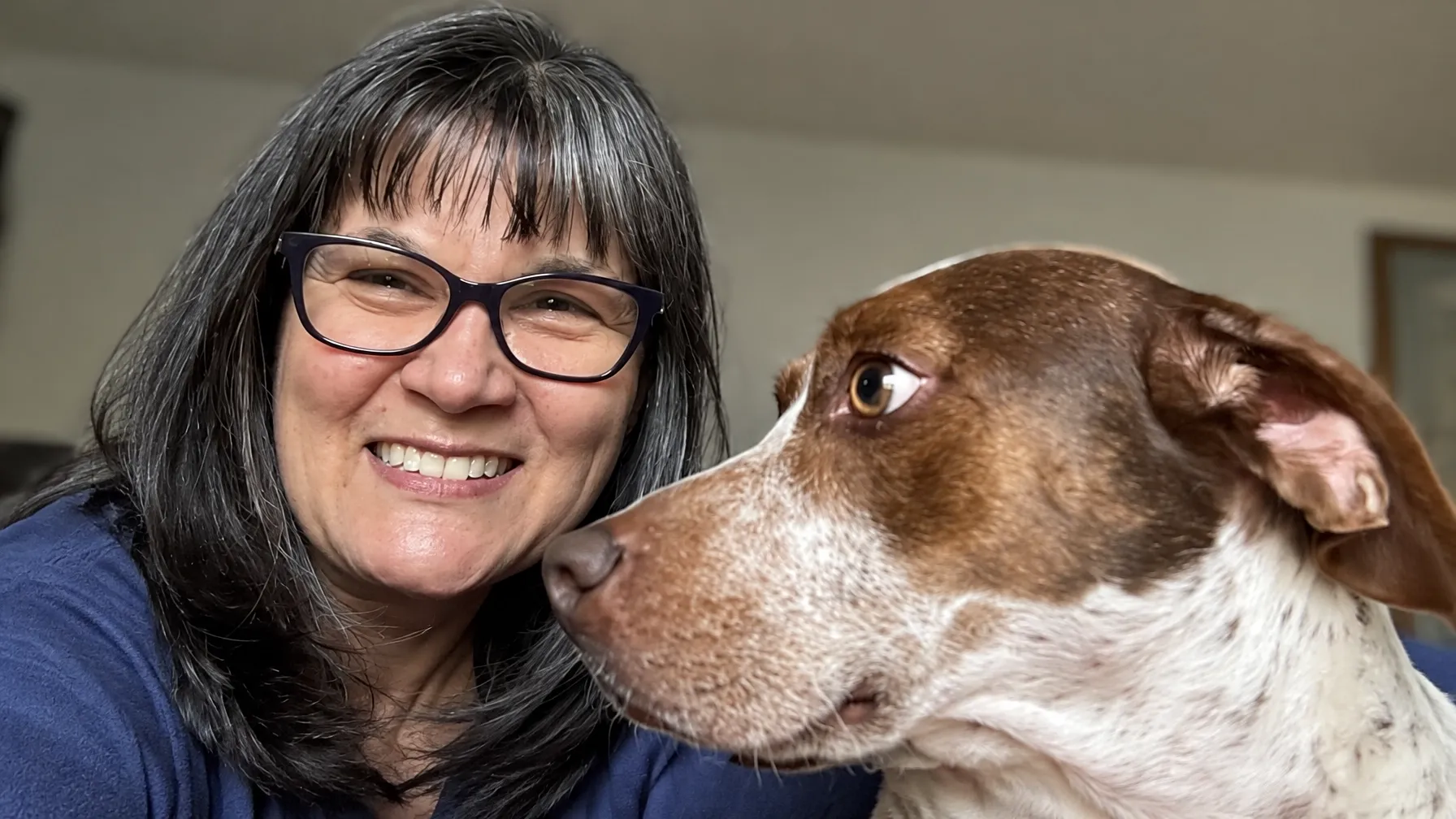 Michelle smiling beside a brown-and-white dog